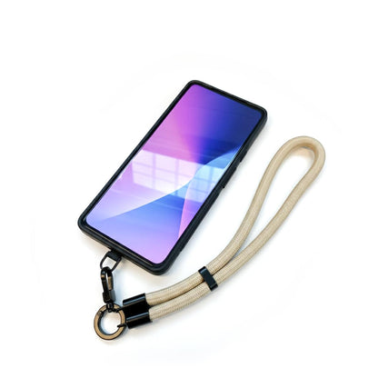 Schwarzes Handy-Patch mit beige-farbenem Schlüsselband und Metallkarabiner vor weißem Hintergrund.
