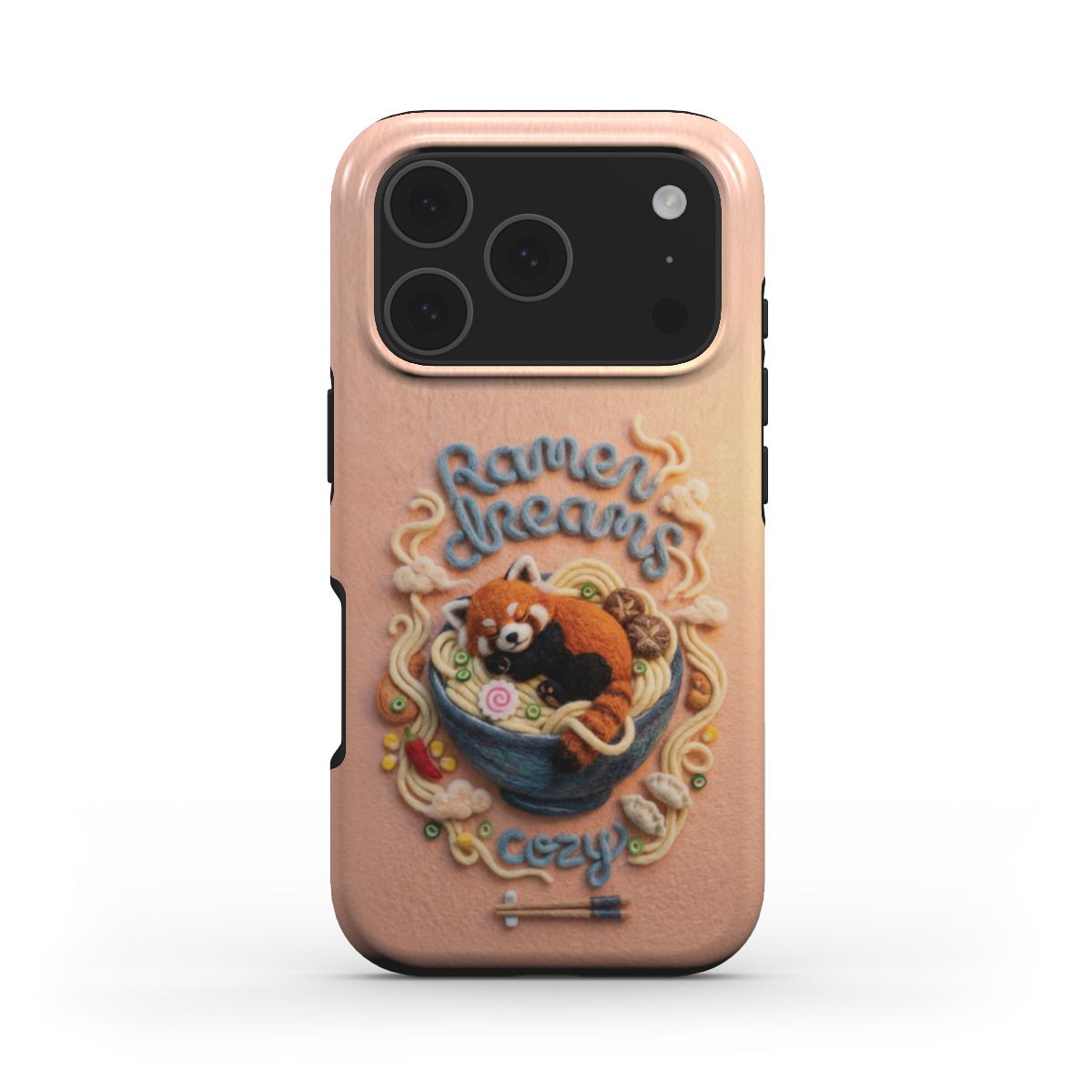 Frontalansicht einer Handyhülle im „Cozy Art“-Stil. Das Motiv zeigt einen niedlichen Roten Panda, der auf Ramen-Nudeln in einer blauen Schüssel schläft. Der Text „Ramen Dreams“ oben und „Cozy“ unten ist in einer verspielten, dreidimensional wirkenden Woll-Optik gestaltet, ergänzt durch kleine Filz-Details wie Pilze und Stäbchen.