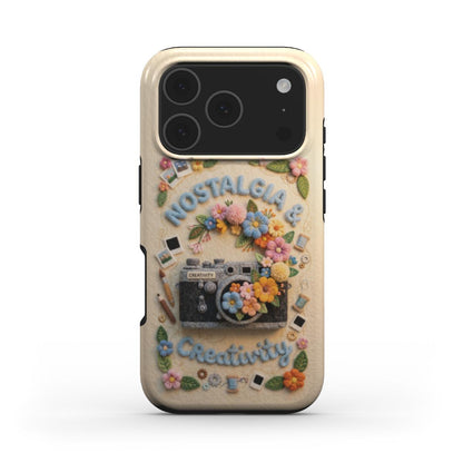 Frontalansicht einer Handyhülle mit textilem Kunstdesign. Im Zentrum steht eine gestickte Vintage-Kamera, umrahmt von Filz-Blumen, kleinen Polaroids und Nähutensilien. Der Text „Nostalgia & Creativity“ ist in hellblauer Relief-Schrift oben und unten platziert.