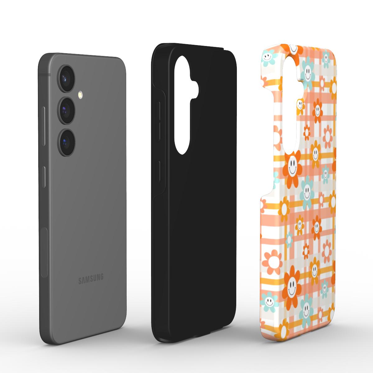 Explosionsansicht: Smartphone, schwarze TPU-Innenschale und bedruckte PC-Außenschale im Smiley-Blumen-Karo-Design.